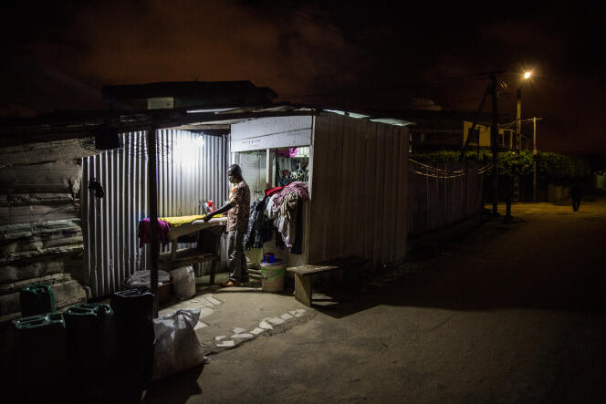 Abdallah travaille dans son échoppe, dans le quartier de la Palmeriaie, à Abidjan, jusque tard dans la nuit.