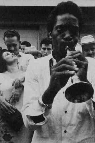 Un musicien de rue joue pour les passants, 1965.