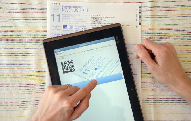 Une personne utilise une tablette près d'une déclaration papier des revenus de l'année 2012.