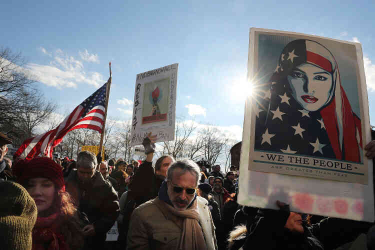A New York, les manifestants se sont réunis à Battery Park, un parc donnant sur la statue de la Liberté. Ici, une femme brandit une pancarte où on peut lire « nous sommes plus grand que la peur » sous l’image d’une femme voilée avec le drapeau américain.