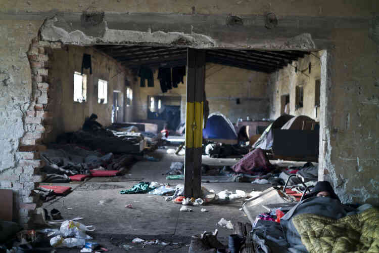 Un refugié aghan allongé sur un couchage de fortune, dans un entrepôt abandonné.