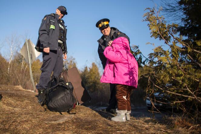 Un agent de la Royal Canadian Mounted Police ajuste la veste de la fille d’une famille de quatre personnes arrivée illégalement au Canada, près de Hemmingford, au Québec, le 28 février.