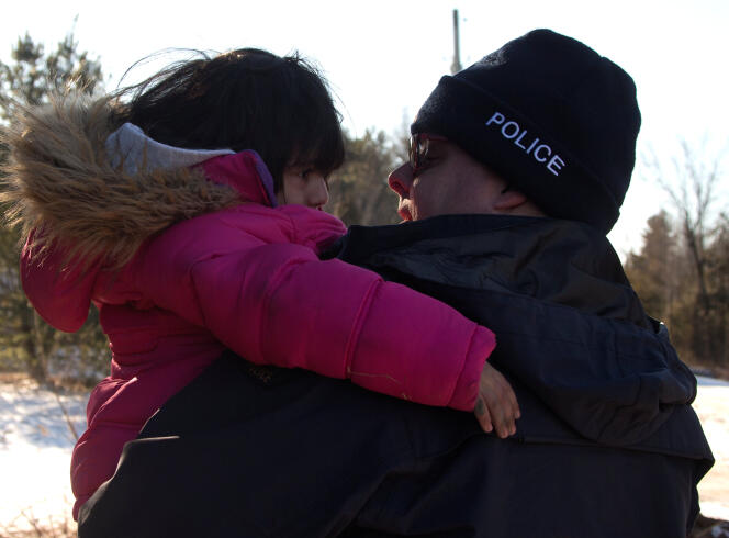 Un policien canadien porte jusqu’à la voiture une enfant qui vient de traverser clandestinement la frontière avec les Etats Unis à Hemminford (Quebec) le 5 mars.