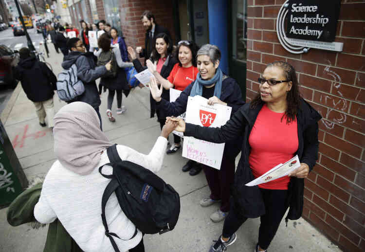 L’enseignante Pia Martin salue les étudiants qui arrivent à l’Académie des sciences à l’occasion de la manifestation « Un jour sans femme » à Philadelphie le mercredi 8 mars. Les femmes sont invitées à rester à la maison et à ne pas dépenser d’argent pour montrer leur impact sur la société américaine.