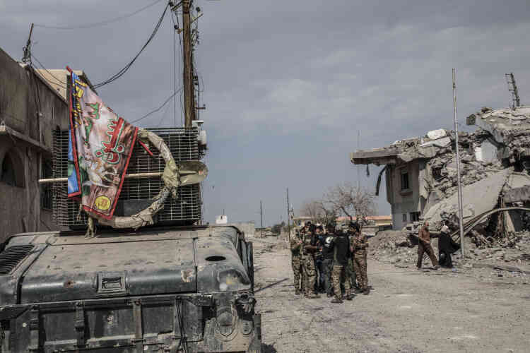 Des combattants de la police fédérale, drapeau religieux chiite exhibé sur le Humvee, dans les quartiers repris à l'EI, le 8 mars.