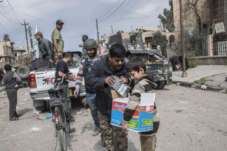 Des membres de la Mobilisation populaire chiite distribuent de la nourriture et des cigarettes dans les quartiers de Mossoul-Ouest repris par les divisions de réaction d’urgence, le 8 mars.