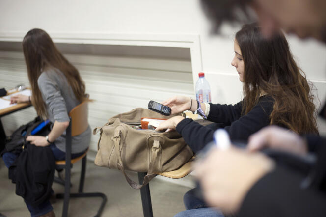 Une élève éteint son téléphone portable avant l’épreuve de philosophie du baccalauréat au lycée Lavoisier à Paris, le 18 juin 2012.