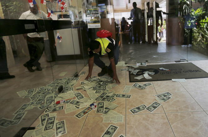 Un syndicaliste ramasse des prospectus ayant l’apparence de billets de banque dans le hall d’entrée de Mossack Fonseca lors d’une manifestation à Panama City le 13 avril 2016.