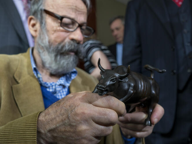 Le sculpteur Arturo Di Modica tient un modèle du « Charging Bull » lors de sa conférence de presse, le 12 avril 2017, à New York.