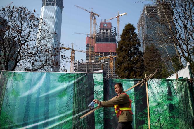 Ouvrier passant devant des bâtiments en construction à Pékin, le 16 avril.