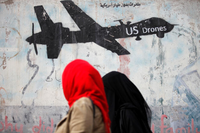 Deux femmes passent devant un graffiti contre les bombardements effectués au Yémen par les drones de l’armée américaine. A Sanaa, le 6 février.