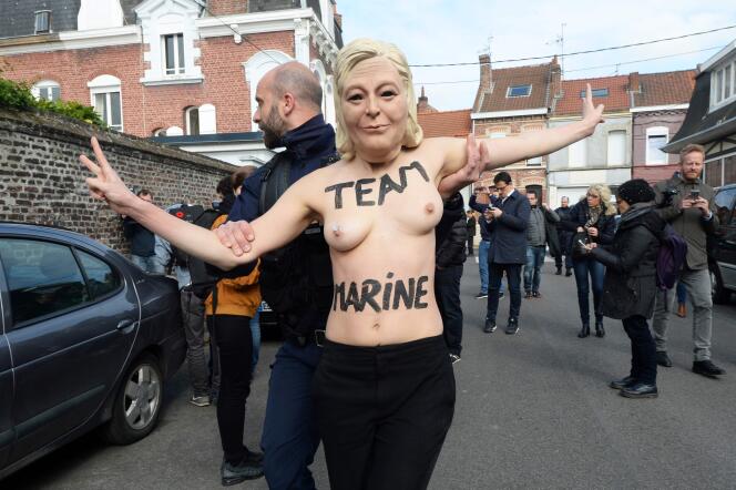 Une militante Femen lors de son interpellation dimanche, un masque de Marine Le Pen sur la tête.