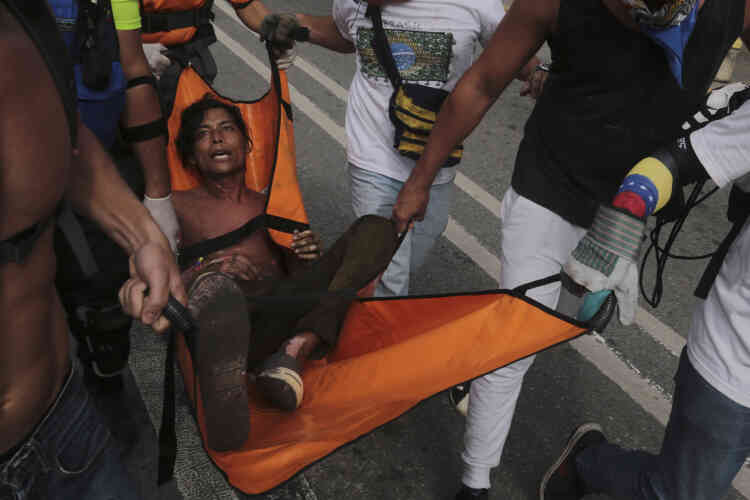 Un homme est évacué après avoir été brûlé lorsque des manifestants ont incendié une moto de la Garde nationale bolivarienne, mercredi 3 mai, à Caracas.