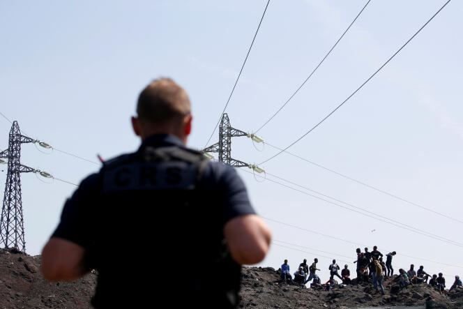 Un policier surveille des migrants à Calais, le 1er juin.