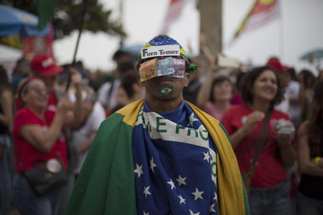 Un manifestant a couvert son visage de billets pour protester contre Michel Temer accusé de corruption, à Rio de Janeiro le 28 mai.
