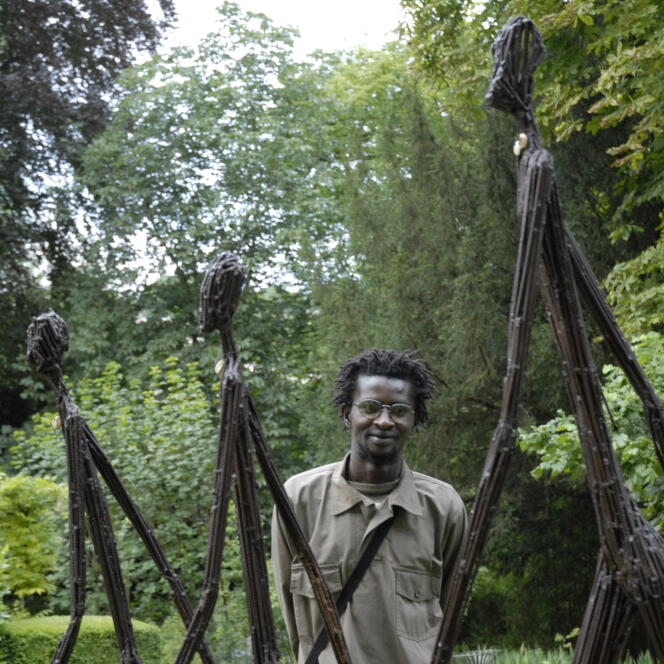 Portrait de Ndary Lo posant derrière sa sculpture 