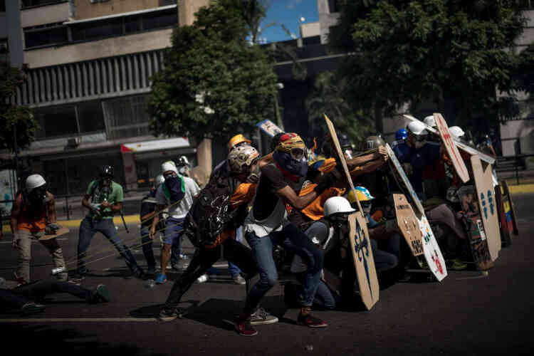 Les manifestants se protègent alors qu’une catapulte est envoyée sur les forces de l’ordre, le 20 mai.