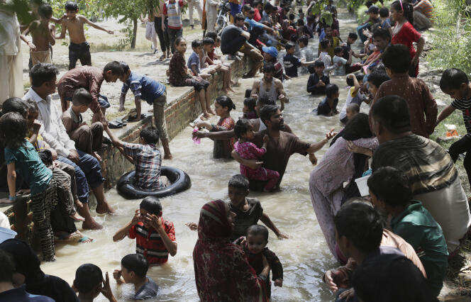 Des familles se rafraîchissent dans l’eau d’un ruisseau lors d’une canicule à Lahore, au Pakistan, le 4 juin.
