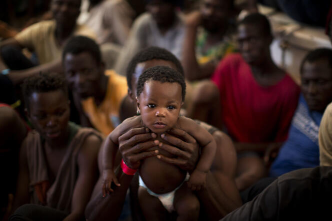 Un Nigerian tient dans ses bras son bébé âgé de six mois à bord d’un navire de sauvetage, en route pour un port italien, le 16 juin.