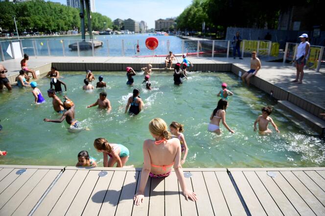 Des enfants se baignent dans le petit bassin de 40 centimètres d’eau inauguré mardi 18 juillet, dans le bassin de La Villette, à Paris.