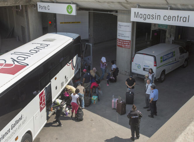 Des demandeurs d’asile déchargent leurs affaires en arrivant au stade olympique de Montréal le 2 août 2017.