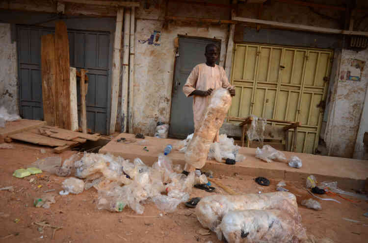 Un jeune homme rassemble les sacs en plastique qui traînent après la fermeture des magasins proches du marché de Kantin Kwari, le 10 mai à Kano.
