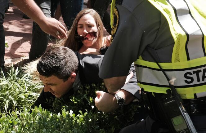 L’organisateur du rassemblement « Unite the Right », Jason Kessler, aidé par la police après avoir été attaqué par une femme pendant sa conférence de presse à Charlottesville (Virginie), le 13 août 2017.