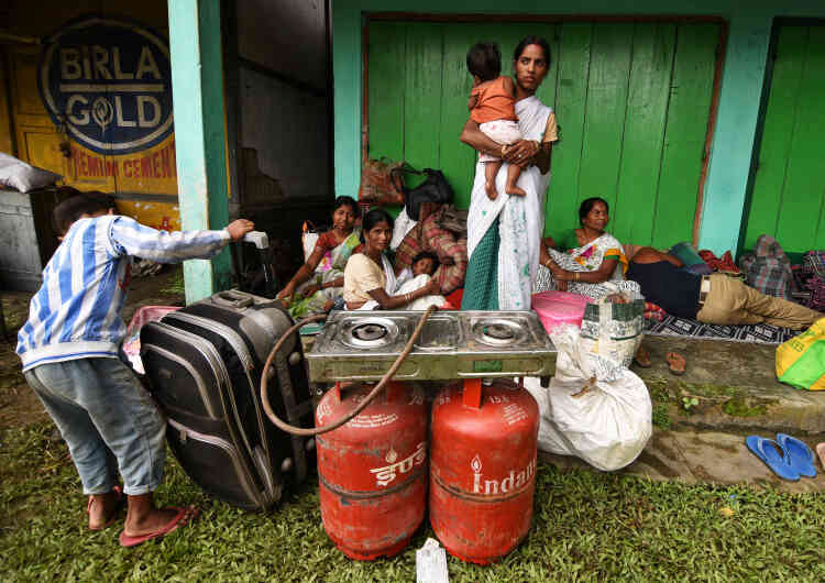 Des familles touchées par les inondations se réfugient devant un magasin et attendent les secours dans la région de Jakhalabandha dans le district de Nagaon, dans le nord-est de l’Assam.