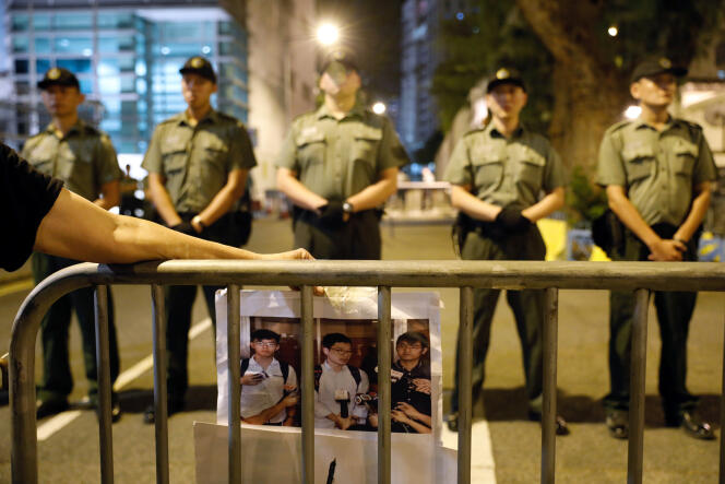 Un manifestant tenant la photo des trois opposants à l’emprise du régime chinois condamnés, le 17 août, à des peines de prison ferme à Hongkong, le 18 août.