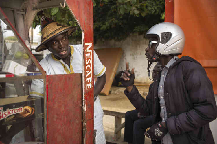 Abba Diatta, le journaliste de Zik FM qui couvre le trafic routier à Dakar, échange avec un marchand de rue. Zik FM est l’une des radios les plus écoutées dans la capitale sénégalaise.