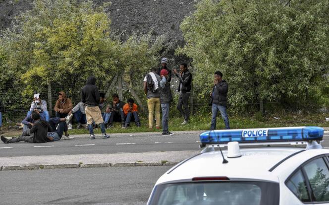 Des policiers surveillent des migrants installés sur un bord de route, aux abords de Calais (Pas-de-Calais), le 16 août.
