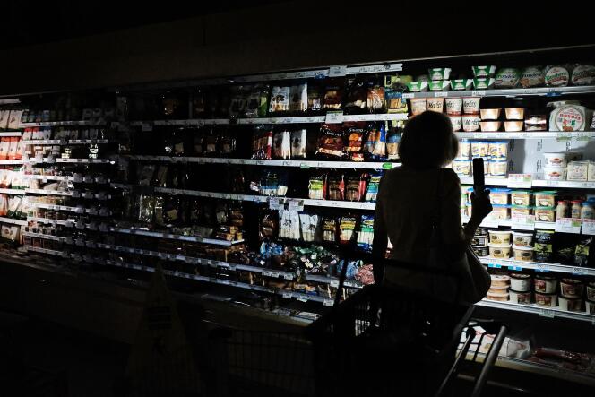 Des habitants de Naples, en Floride, font leurs courses à la lueur de leur téléphone portable dans un supermarché sans électricité, le 13 septembre.