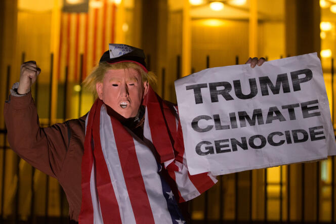Un homme portant un masque de Donald Trump, brandit une pancarte « Trump, climat, génocide » le 18 novembre à Londres.