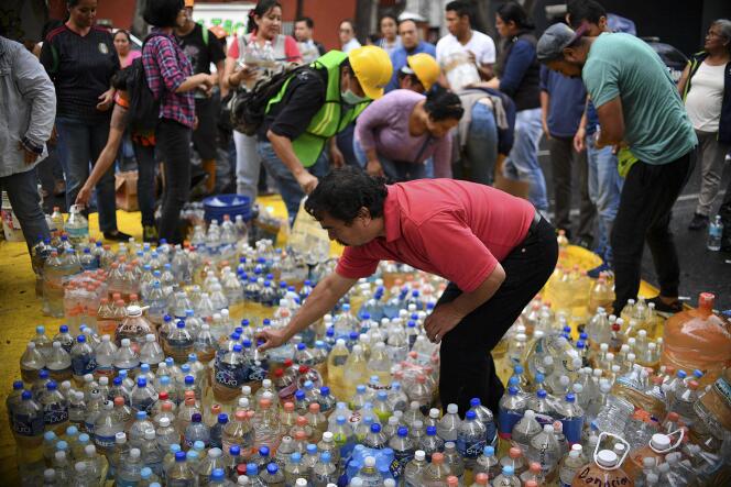 Des volontaires recueillent des bouteilles d’eau, à Mexico, le 21 septembre.