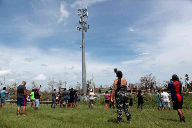 Des Portoricains, rassemblés autour d’une antenne relais, tentent de capter le réseau téléphonique mobile, à Dorado. « Le réseau de télécommunications est presque entièrement détruit », rapporte l’AFP.