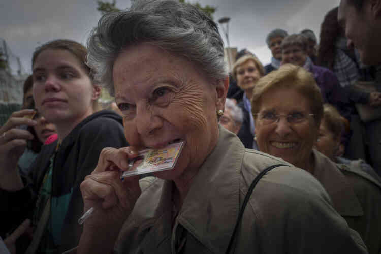 Une électrice déterminée à voter, serre sa carte d’identité entre ses dents. Beaucoup de policiers en civil se sont mêlés aux files d’attente devant les bureaux de vote.