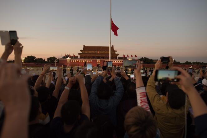 Des chinois photographient la mise en berne du drapeau sur la place Tiananmen à Pekin, le 28 septembre.