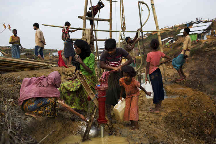 Les réfugiés rohingya collectent l’eau d’un puits alors que, derrière, les Bangladais creusent un autre puits, dans le camp d’extension de Kutupalong.