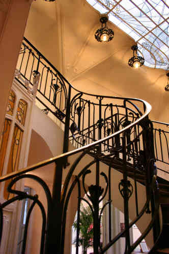 A l’intérieur, le grand hall avec son spectaculaire escalier et ses fontes ornées, ainsi que ses vitraux.