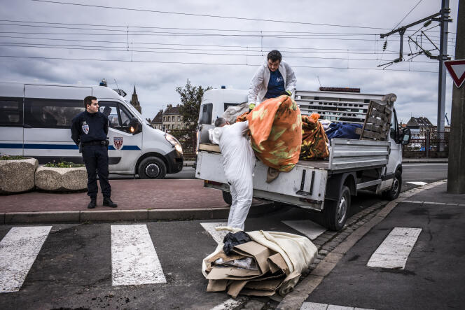 Des agents de la ville de Calais récupèrent les biens des migrants, le 5 décembre. OLIVIER PAPEGNIES/COLLECTIF HUMA POUR « LE MONDE »