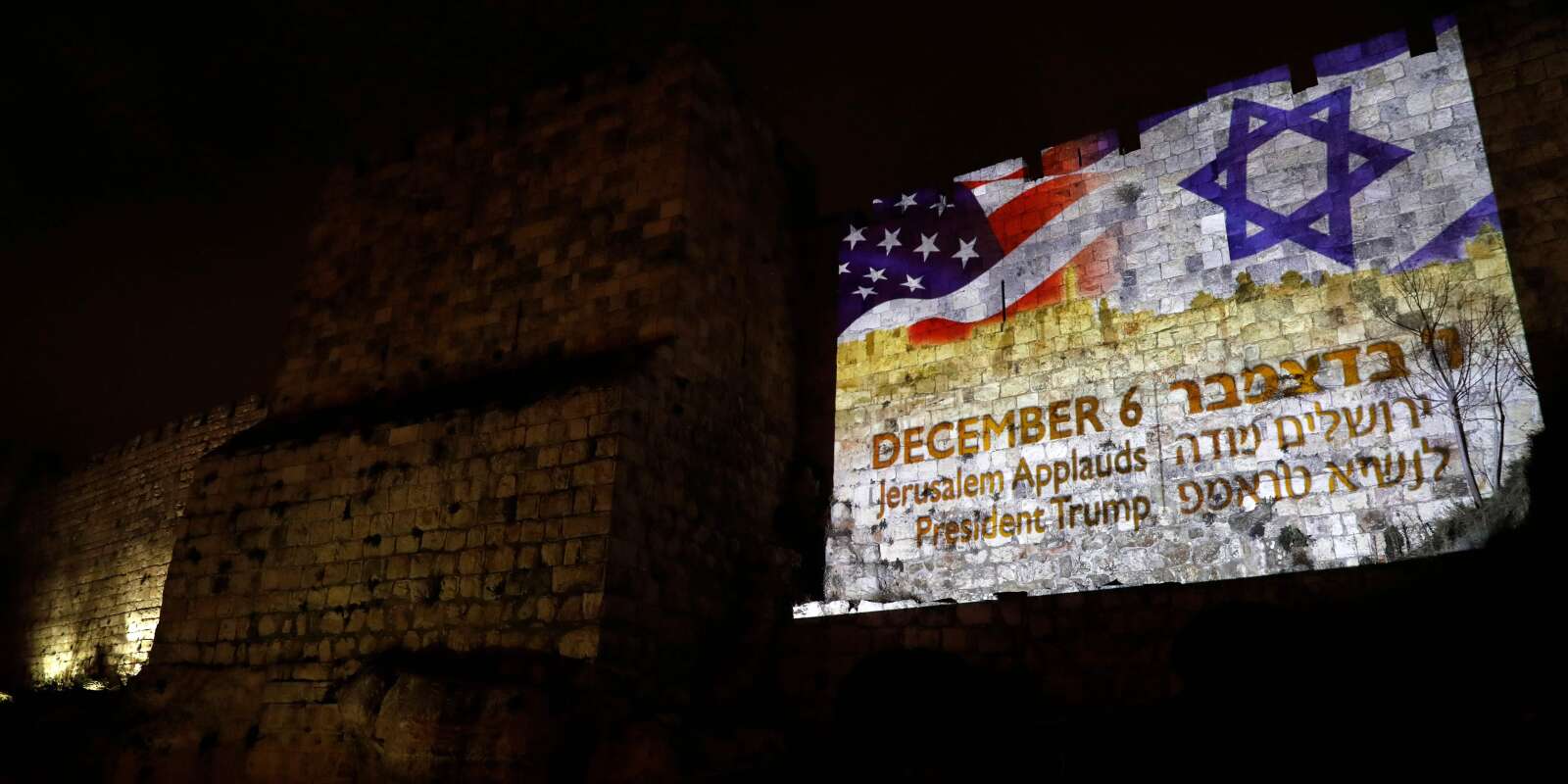 A picture taken on December 6, 2017 shows a giant US flag screened alongside Israel's national flag by the Jerusalem municipality on the walls of the old city. US President Donald Trump recognized the disputed city of Jerusalem as Israel's capital on December 6, 2017, and kicked off the process of relocating the US embassy there from Tel Aviv. The old city lies in the eastern part of Jerusalem which was under Jordanian control from Israel's creation in 1948 until Israeli forces captured it during the 1967 Six-Day War, and Israel later annexed it in a move not recognised by the international community. / AFP / Ahmad GHARABLI