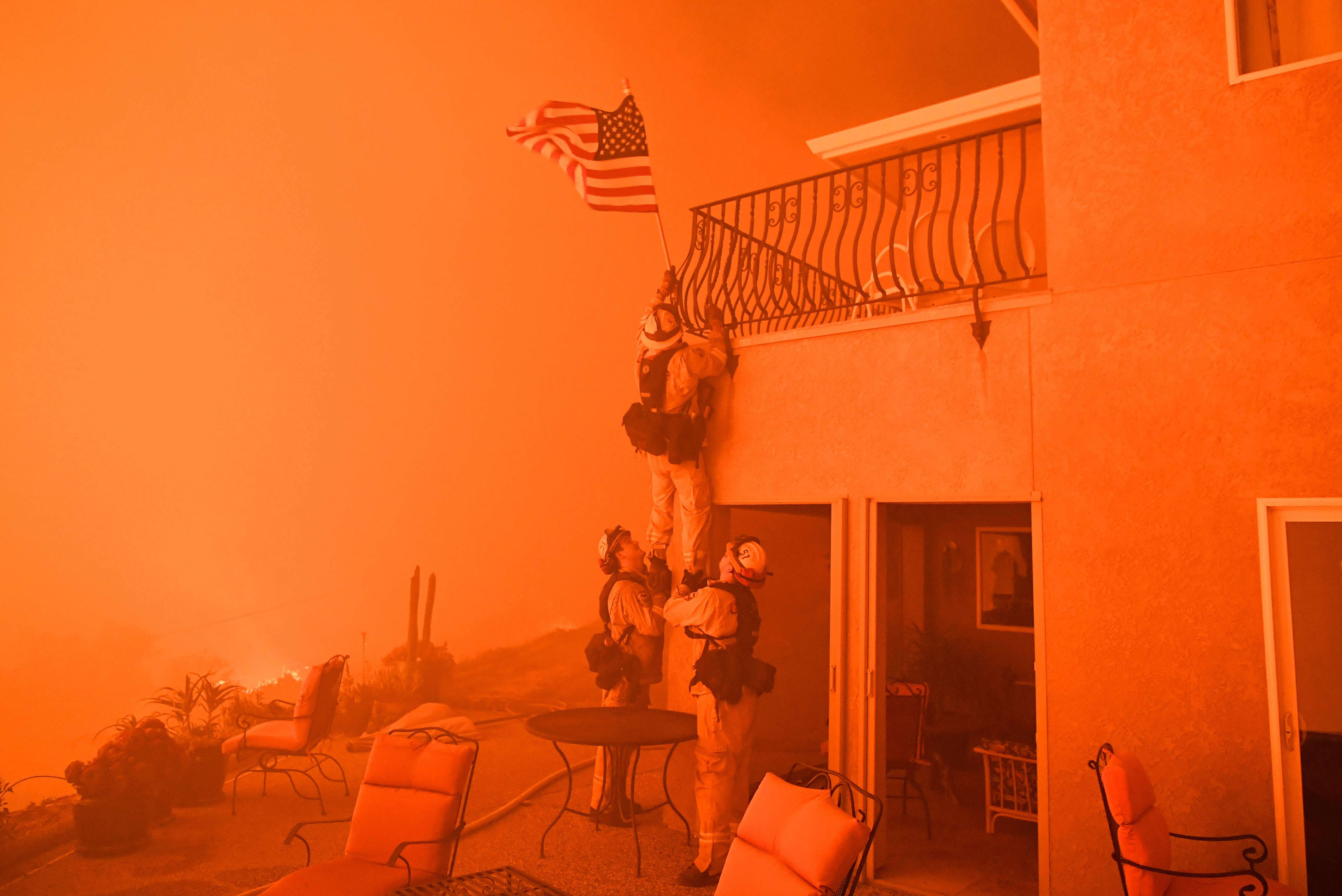 Des pompiers retirent un drapeau d’une maison alors qu’un incendie se rapproche des habitations. Plusieurs centaines de milliers d’hectares sont partis en fumée durant l’année en Californie.