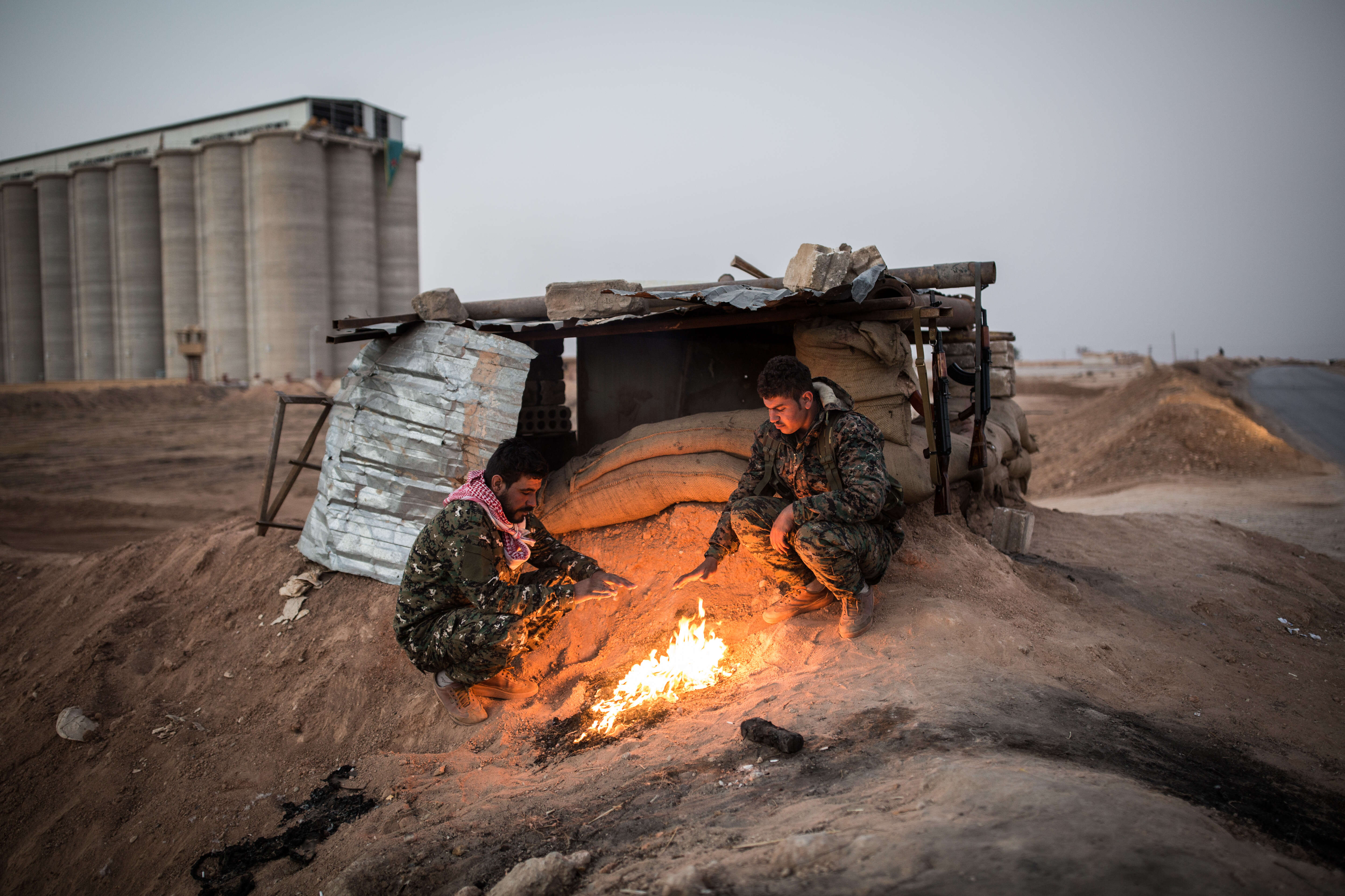 Deux soldats des Forces démocratiques kurdes (FDS) se réchauffent les mains. Ils sont postés à un check-point entre Qamishli et Kobané, sur la route de Rakka. Les FDS, alliance de combattants arabes et kurdes soutenue par les Etats-Unis, ont annoncé avoir « totalement » repris la ville de Rakka à l’organisation Etat islamique, mardi 17 octobre.