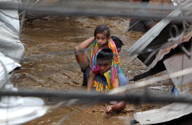 Un officier de police porte un enfant dans les rues innondées de Cagayan City, aux Philippines, le 22 décembre.