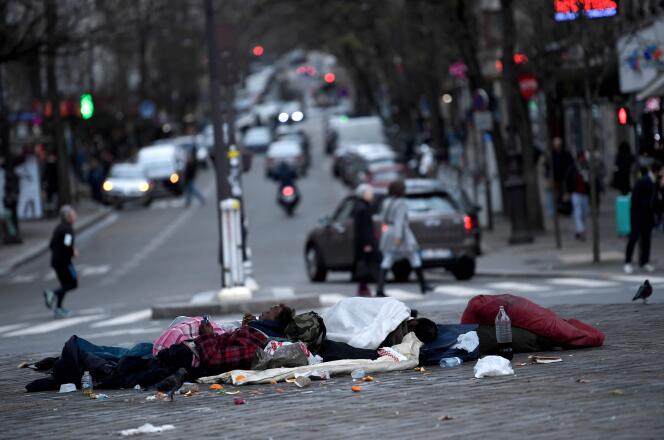 Deux hommes sans domicile étendus sur le sol à un carrefour parisien, le 24 décembre 2017.
