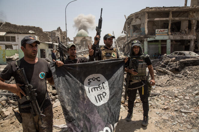 Des soldats célébrent la prise de la mosquée Al-Nouri de Mossoul (Irak), le 2 juillet. Ils ont récupéré un drapeau de l’EI.