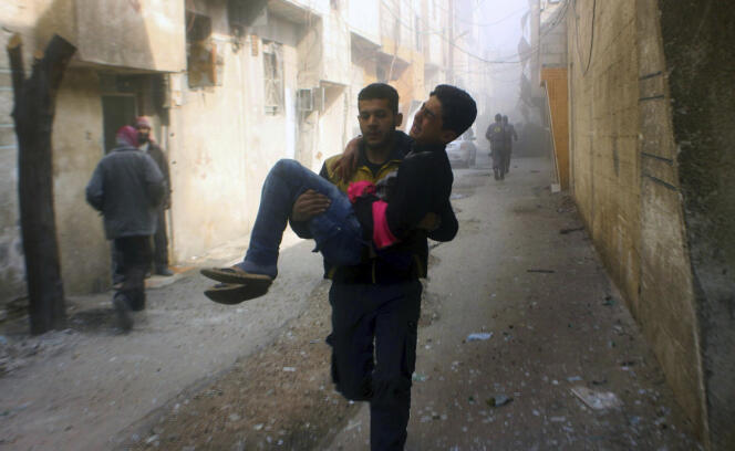 Un membre de la défense civile porte un jeune homme blessé lors d’un bombardement, dans la Ghouta orientale, le 24 février.