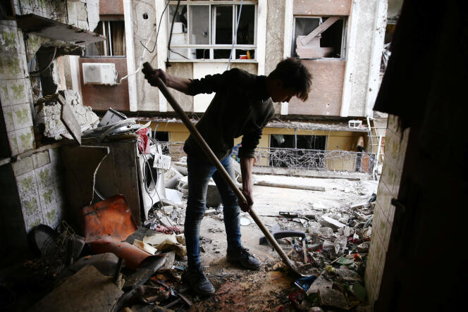 Un adolescent nettoie un appartement endommagé à Douma, le 25 février.