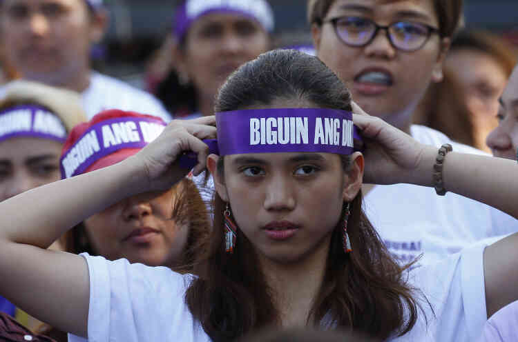 Une manifestante ajuste son bandeau où est écrit « Faire échouer la dictature ! » Des centaines de militantes en chemises roses et mauves ont protesté à Manille,  le 8 mars, contre le président philippin, Rodrigo Duterte, le comptant parmi les pires violeurs des droits des femmes.