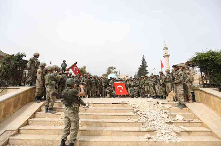 Des soldats turcs posent victorieusement pour une photo de groupe, sur une place de la ville, dimanche.